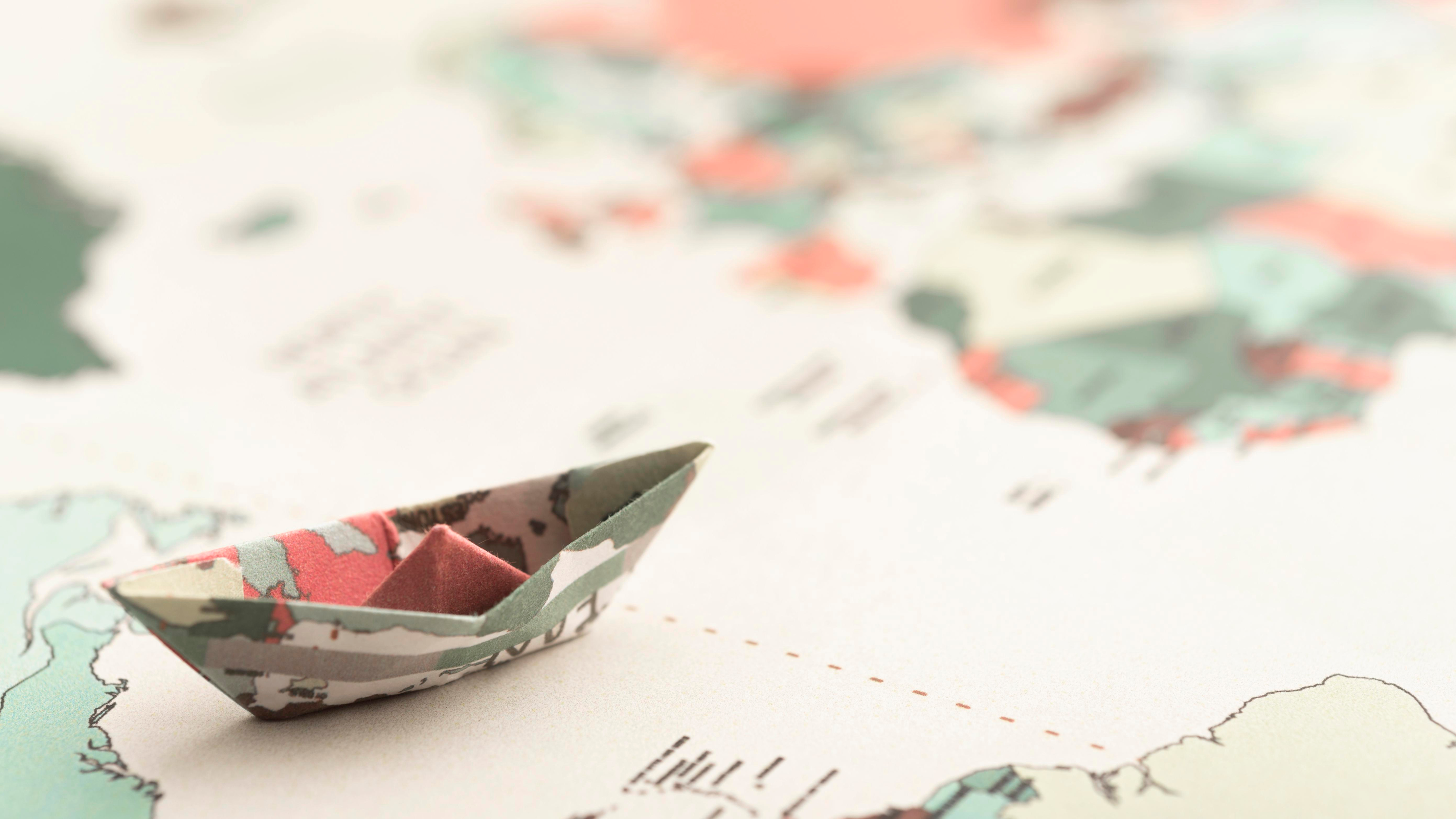 Hero background showing a small origami boat on a world map.